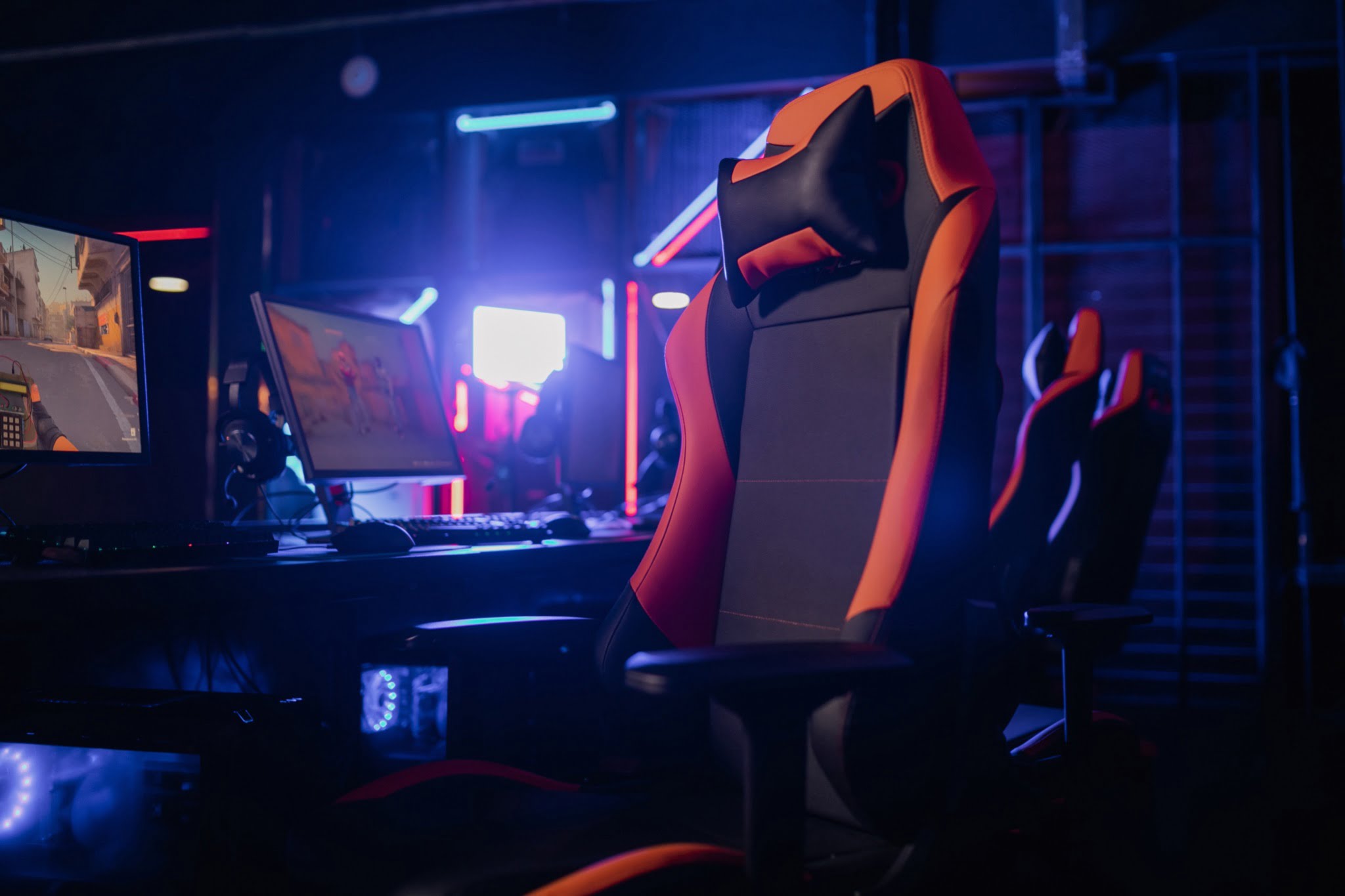 multiple pc and red black gaming chair in a room